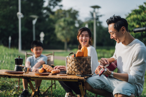 A father playing music for his family whilst on a picnic